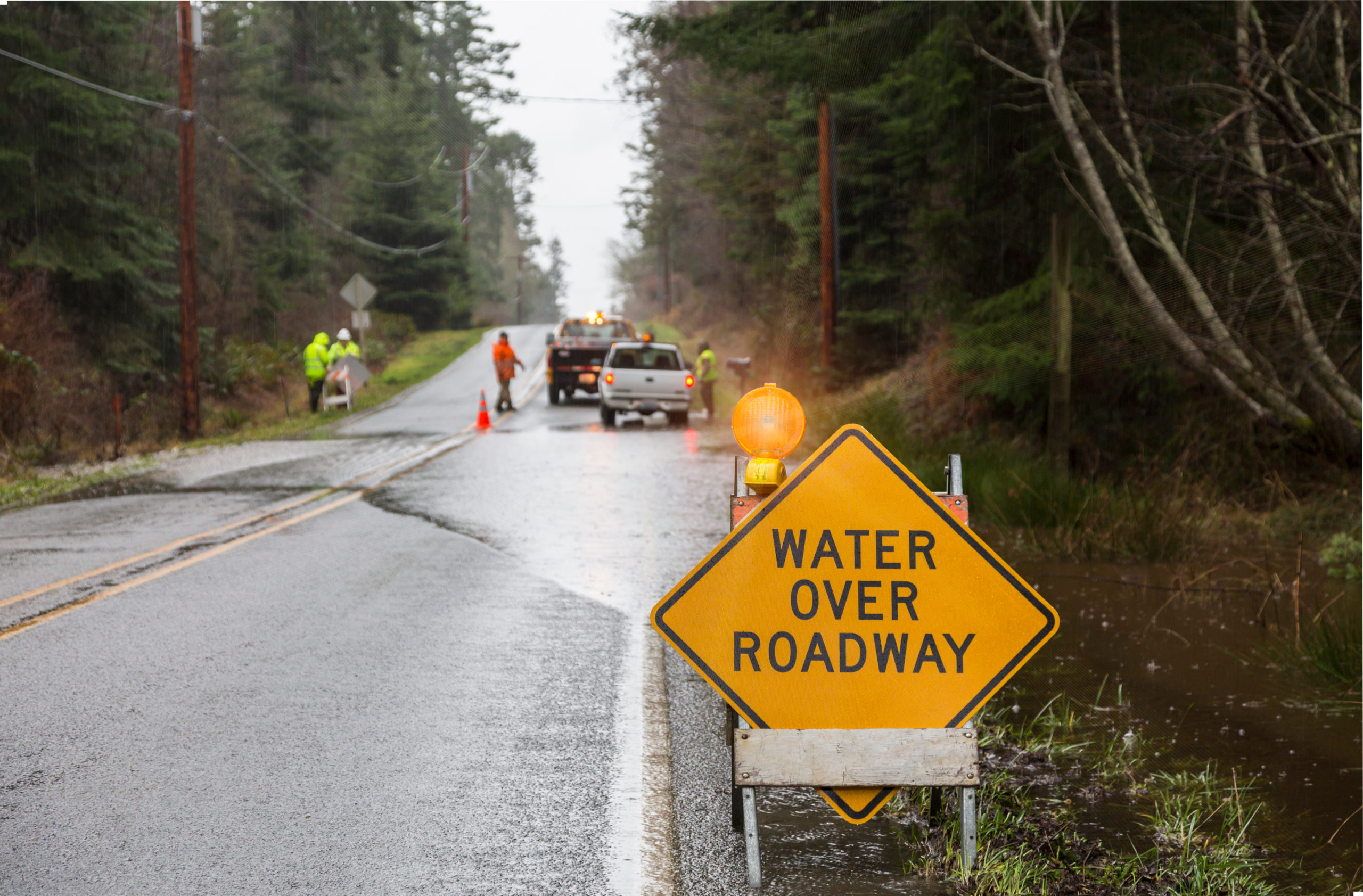 Emergency workers placing warning signs on flooded road