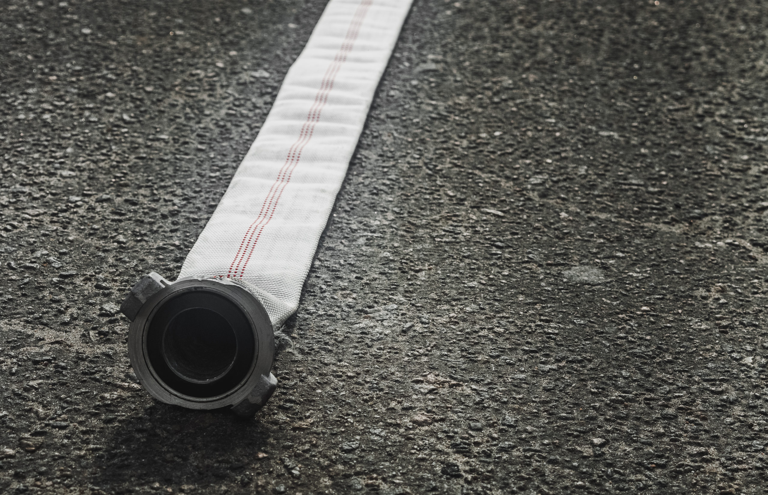 fire hose lying on the dark asphalt